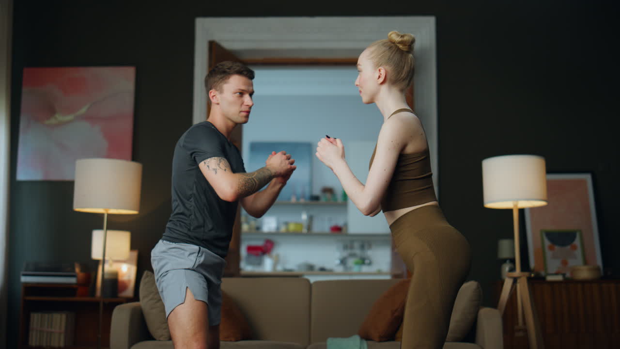 젊은 파트너들이 집에서 함께 체조를 연습하고 가족들이 스트를 하고 있습니다.