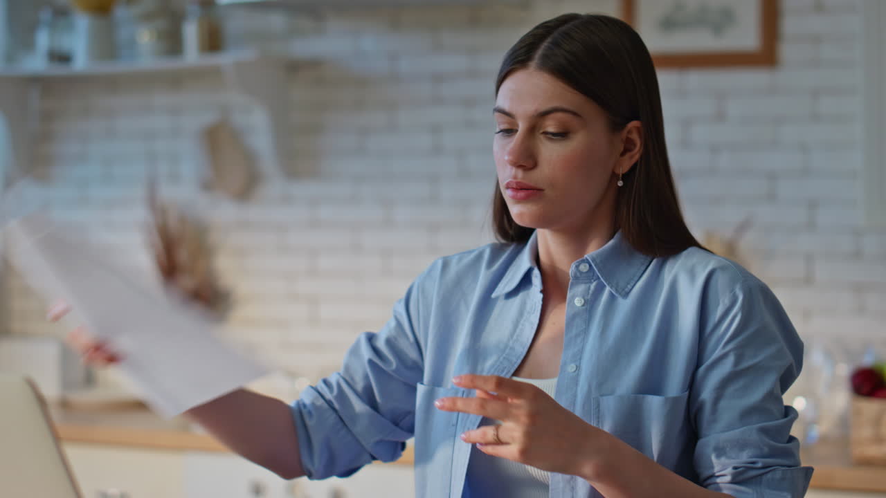Exhausted woman examining documentation working at kitchen workplace closeup