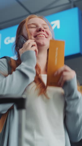 woman looking at boarding pass at the airport and talking on phone