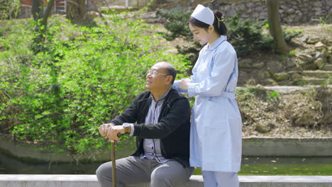 nurse assisting elderly man in an outdoor park setting