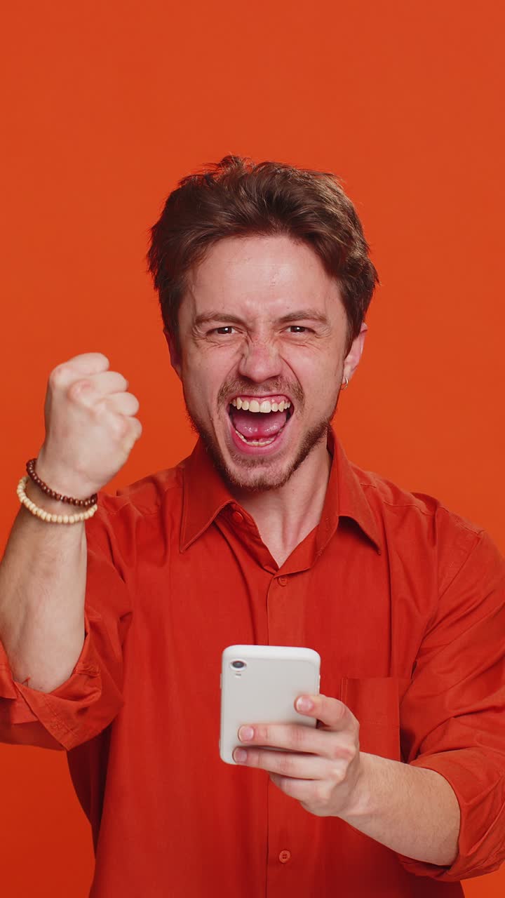 feliz ganador emocionado hombre usar teléfono inteligente celebrar el éxito ganar jugar juego buenas noticias de lotería