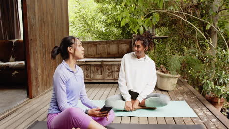 multiracial female friends practicing yoga together on wooden deck, peaceful setting