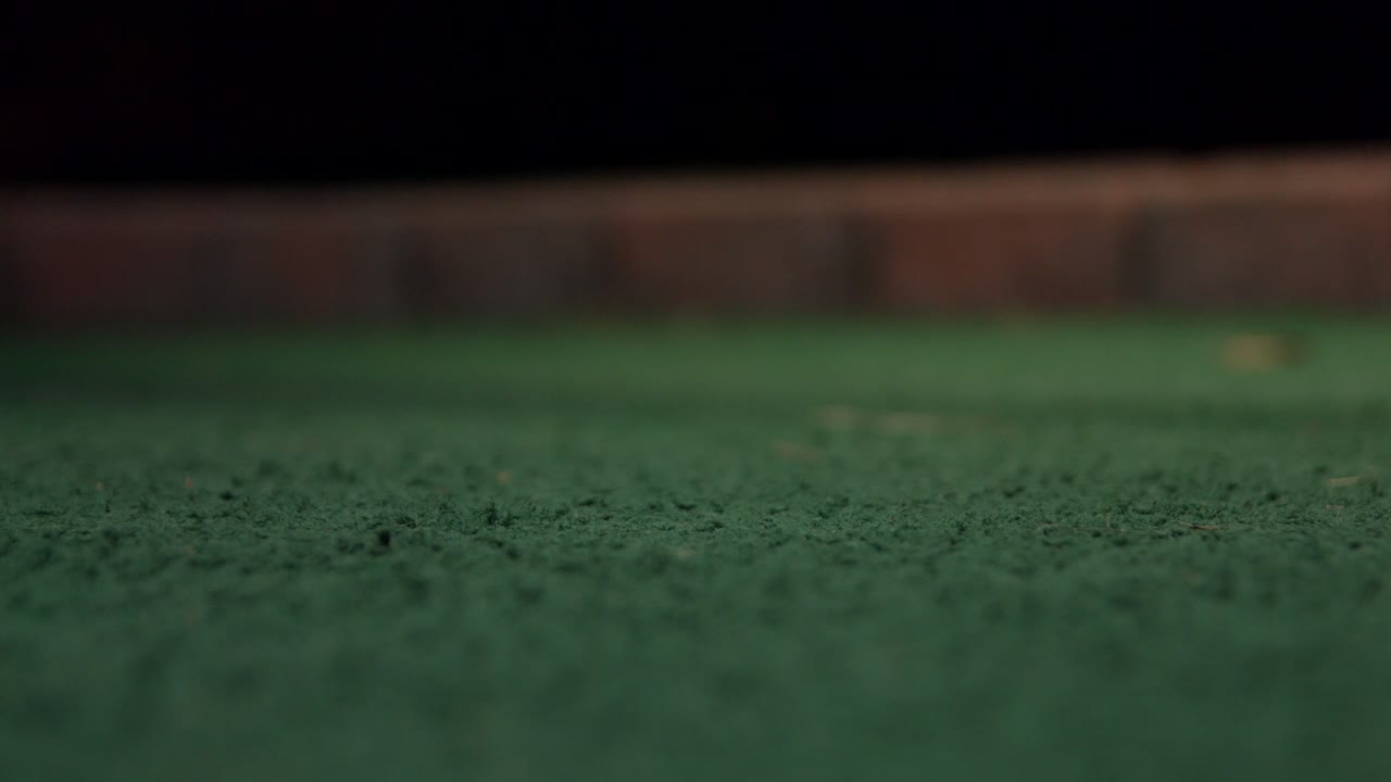 Extrem närbild på en minigolfputter som träffar en gul golfboll
