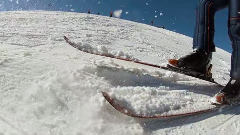 slow motion, taking down snow from ski that goes direct to the camera