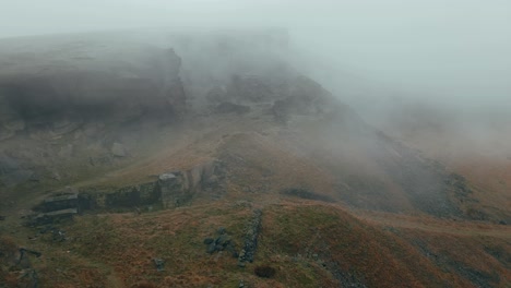 aerial drone view of clouds moving slowly over the pennine hills, on a foggy morning, golden hills and beautiful rocky cliffs and moorlands