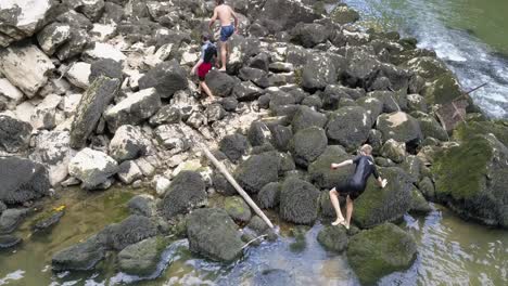 los jóvenes salen del río doubs, caminando sobre grandes rocas con musgo