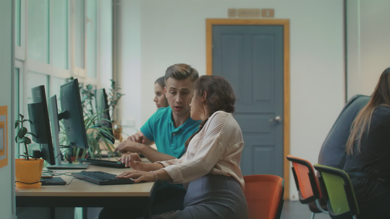 Young woman consulting with colleague about work. Pretty lady looking in pc