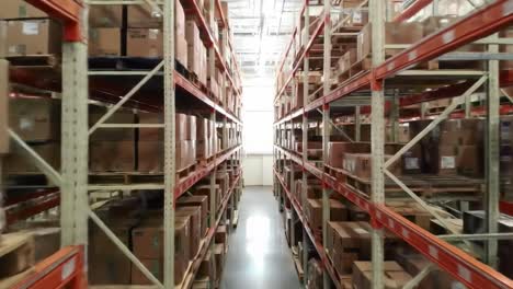 a view through the aisles of a warehouse filled with cardboard boxes, shelving units, and organized storage solutions for efficient logistics operations