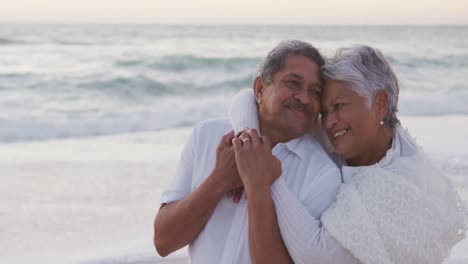 Glückliches-Hispanisches-Frisch-Verheiratetes-älteres-Paar,-Das-Sich-Bei-Sonnenuntergang-Am-Strand-Umarmt