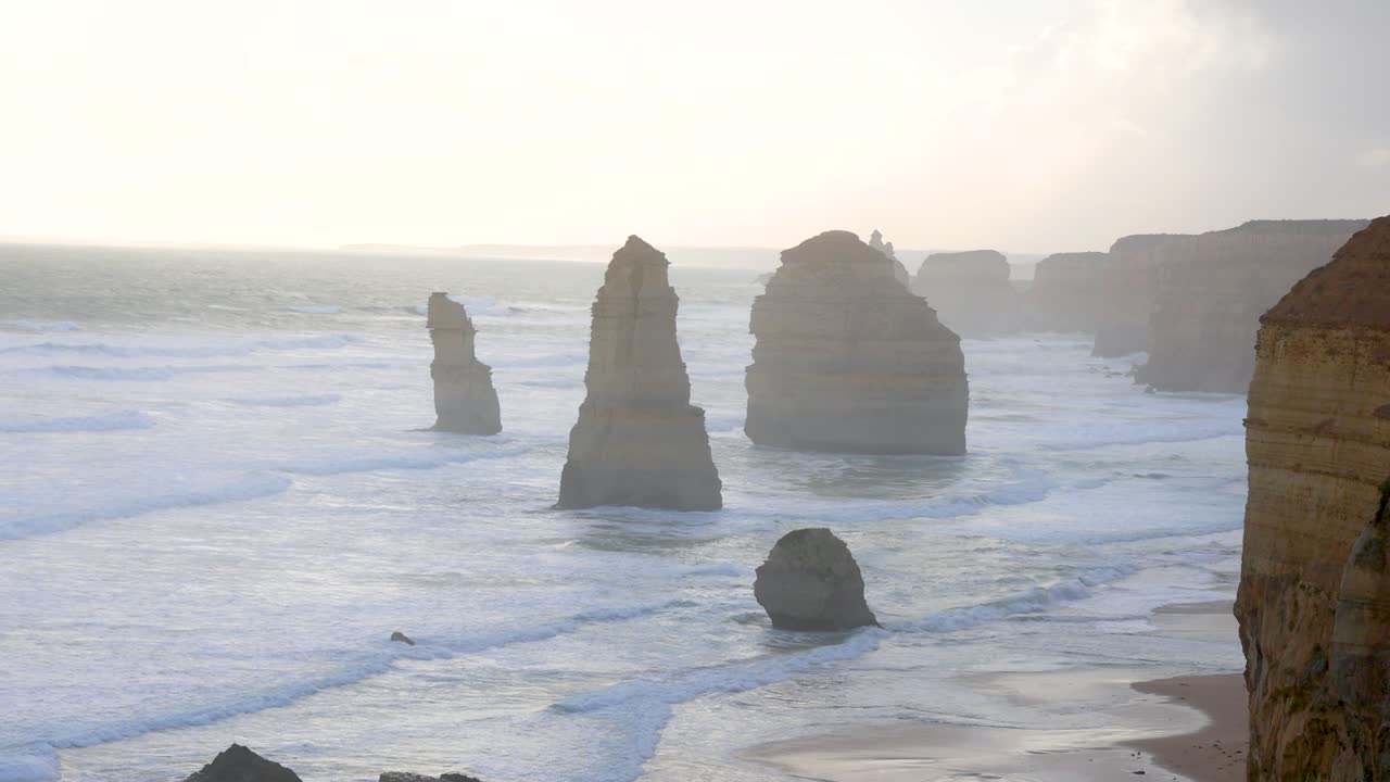 A serene view of the Twelve Apostles rock formations along the Great Ocean Road, captured at sunrise with gentle waves