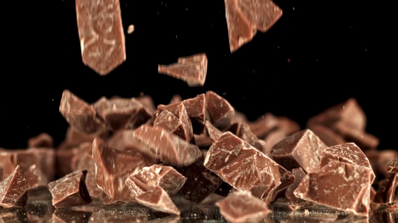 Pezzi di cioccolato che cadono al rallentatore su sfondo nero