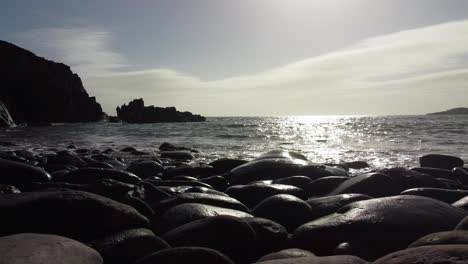calm waves rolling onto pebble beach on sunny day 4k