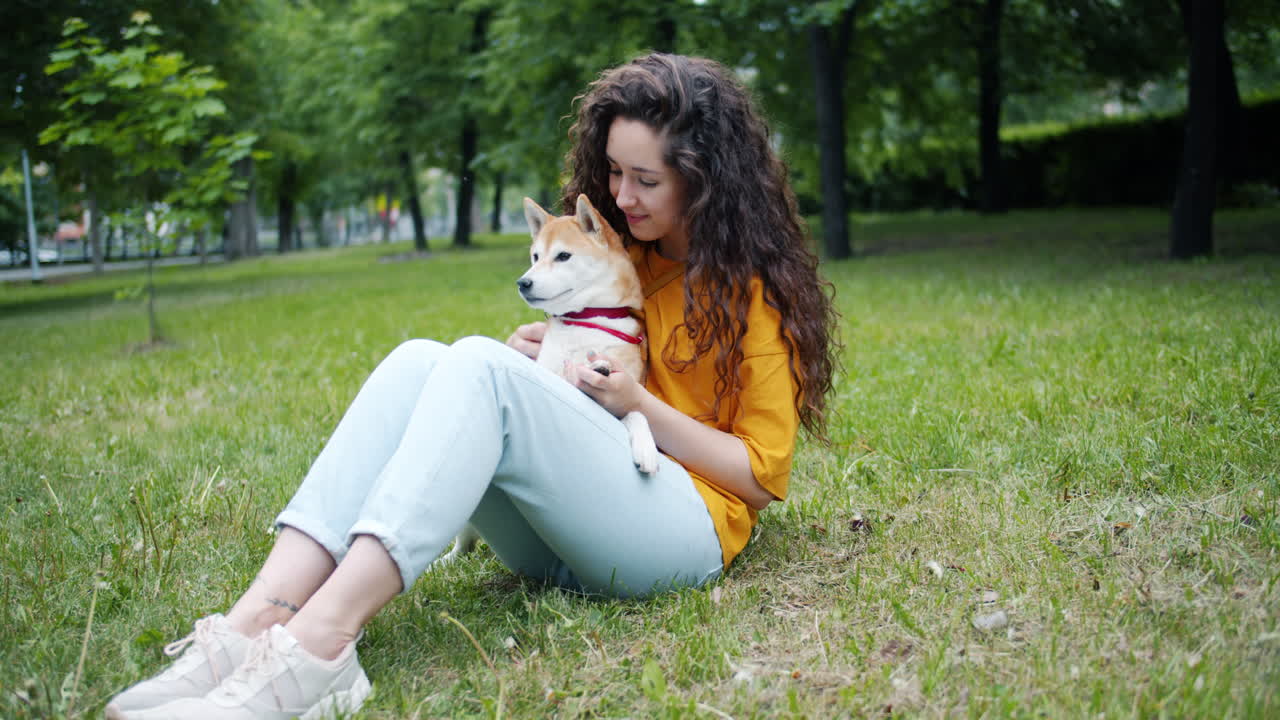 Woman sitting in a park with a Shiba Inu dog