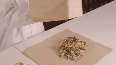 actual footage for an advertisement with the theme of traditional medicine, physician is selecting each dry medicinal herb to package the medicine according to the prescription