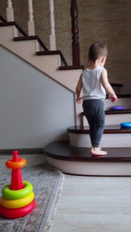 active baby boy runs up the stairs picking his toys. cheerful toddler building a pyramid on the floor. vertical video.