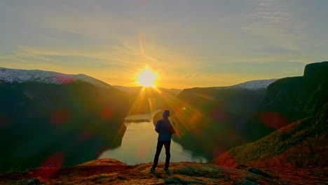 Vista-Trasera-Del-Hombre-Mirando-La-Impresionante-Puesta-De-Sol-Dorada-Sobre-El-Fiordo-Noruego