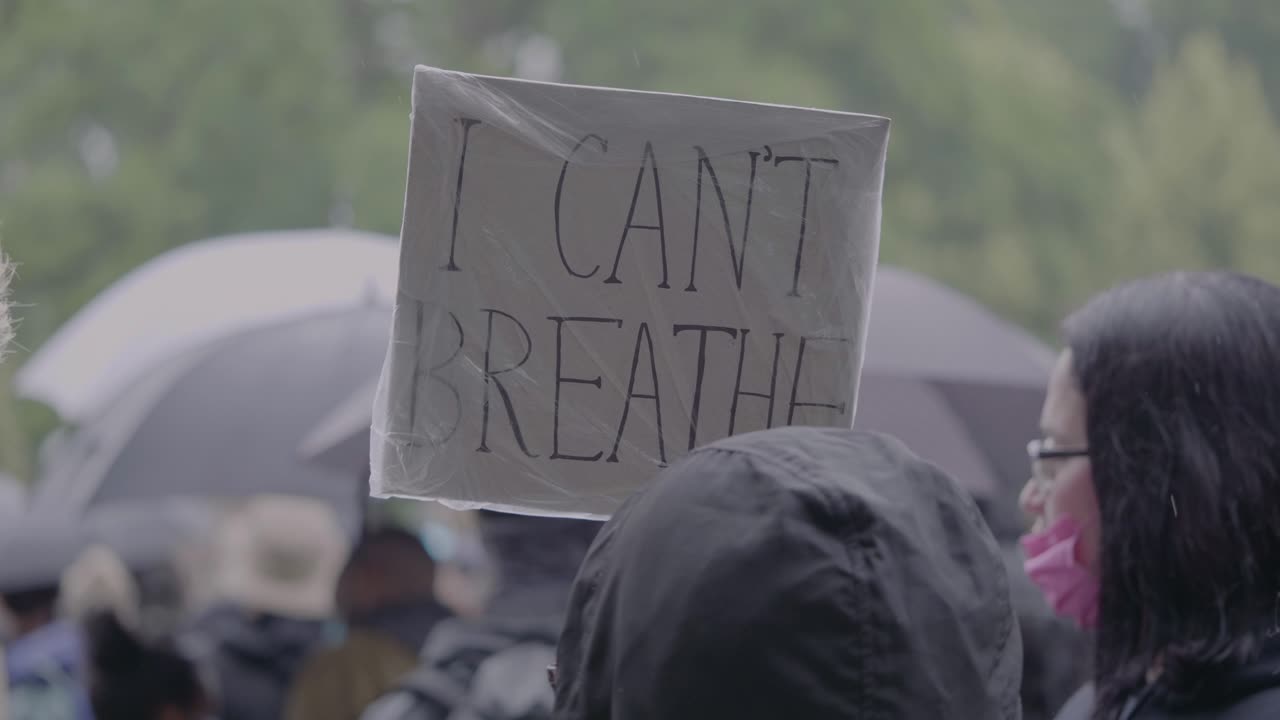 Protester holding sign against racism with text spelling i can't breathe at a black lives matter protest in Stuttgart, Germany.