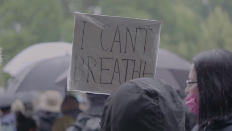 protester holding sign against racism with text spelling i can't breathe at a black lives matter protest in stuttgart, germany.