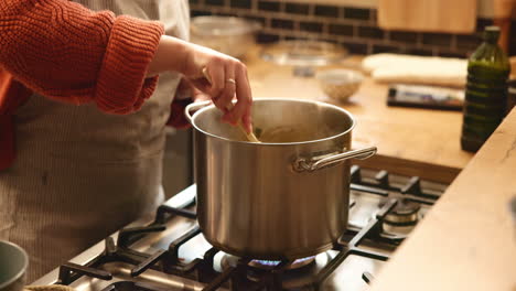 woman cooking soup in kitchen