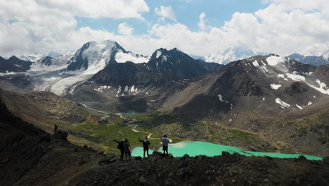 revelador disparo de dron de 3 hombres parados en la cima de la montaña sobre el lago ala-kol en kirguistán
