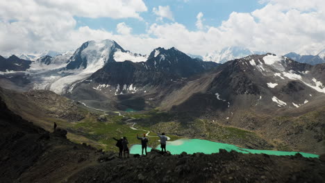 tiro de drone revelador de 3 homens parados no topo da montanha sobre o lago ala-kol no quirguistão