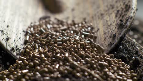 a close-up view of organic soil enrichment process with fertilizer pellets being shoveled into nutrient-rich soil for optimal plant growth and sustainability