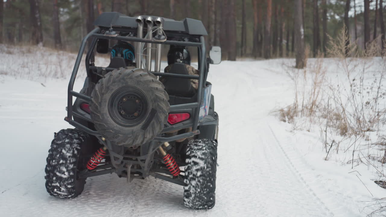 Un fotografo regola la fotocamera su un ATV. Il veicolo motorizzato fa una pausa prima dell'inizio di un'escursione impegnativa nella foresta. Un ATV in posa si trova su un sentiero innevato con il fotografo che si prepara per una spedizione di esplorazione nella foresta.