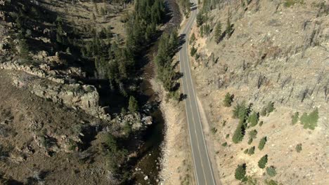 aerial of empty road in canyon next to river in colorado