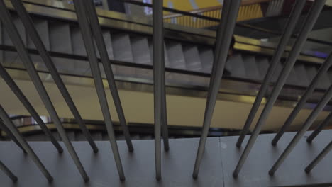 a moving escalator visible through fence bars