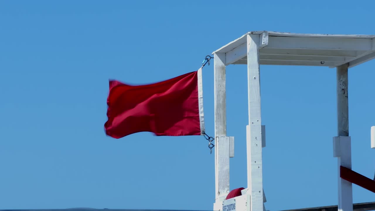 una bandera roja en una estación de socorristas advierte sobre fuertes y peligrosas corrientes de resaca