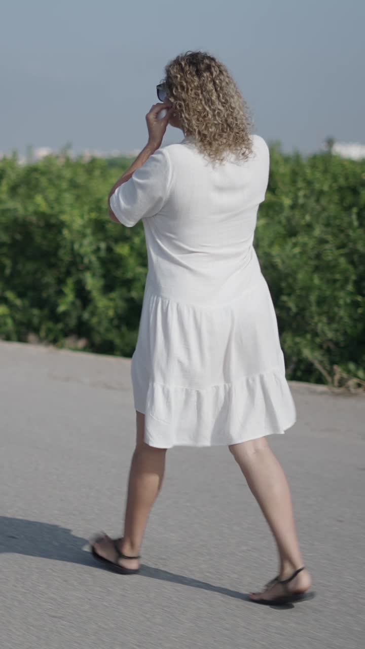 Woman in white dress walking on road