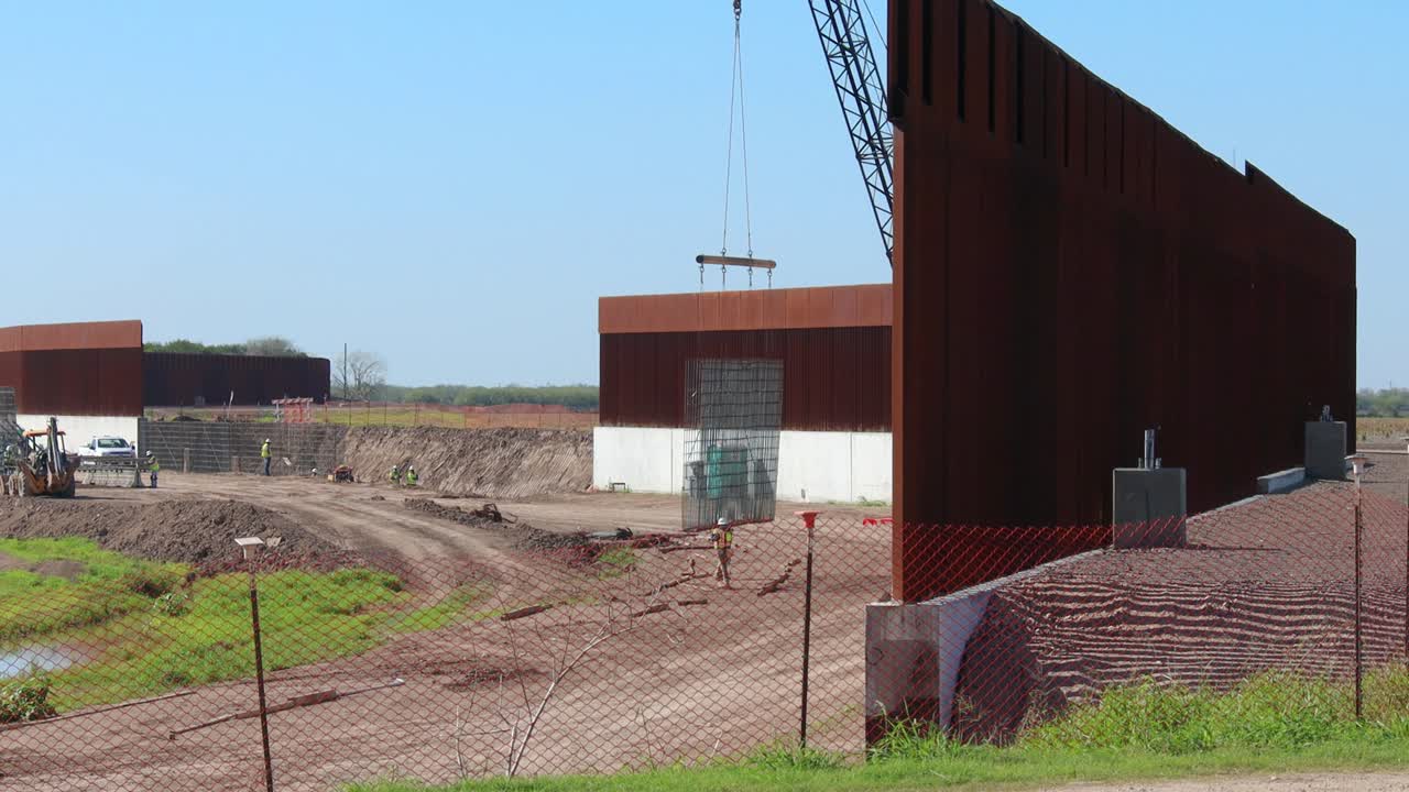 trabajadores de la construcción moviendo varillas de refuerzo para hormigón en el muro fronterizo entre estados unidos y méxico
