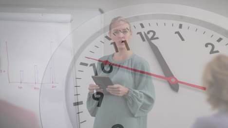 animación de reloj en contra de mujer caucásica sosteniendo una tableta dando una presentación en la oficina