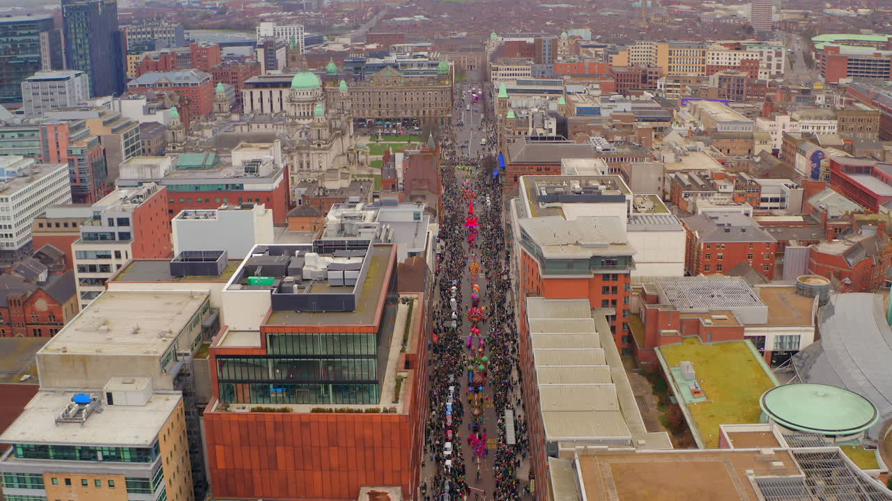 Aerial showcases wide view of St. Patrick’s Day parade across colourful streets of Belfast city centre