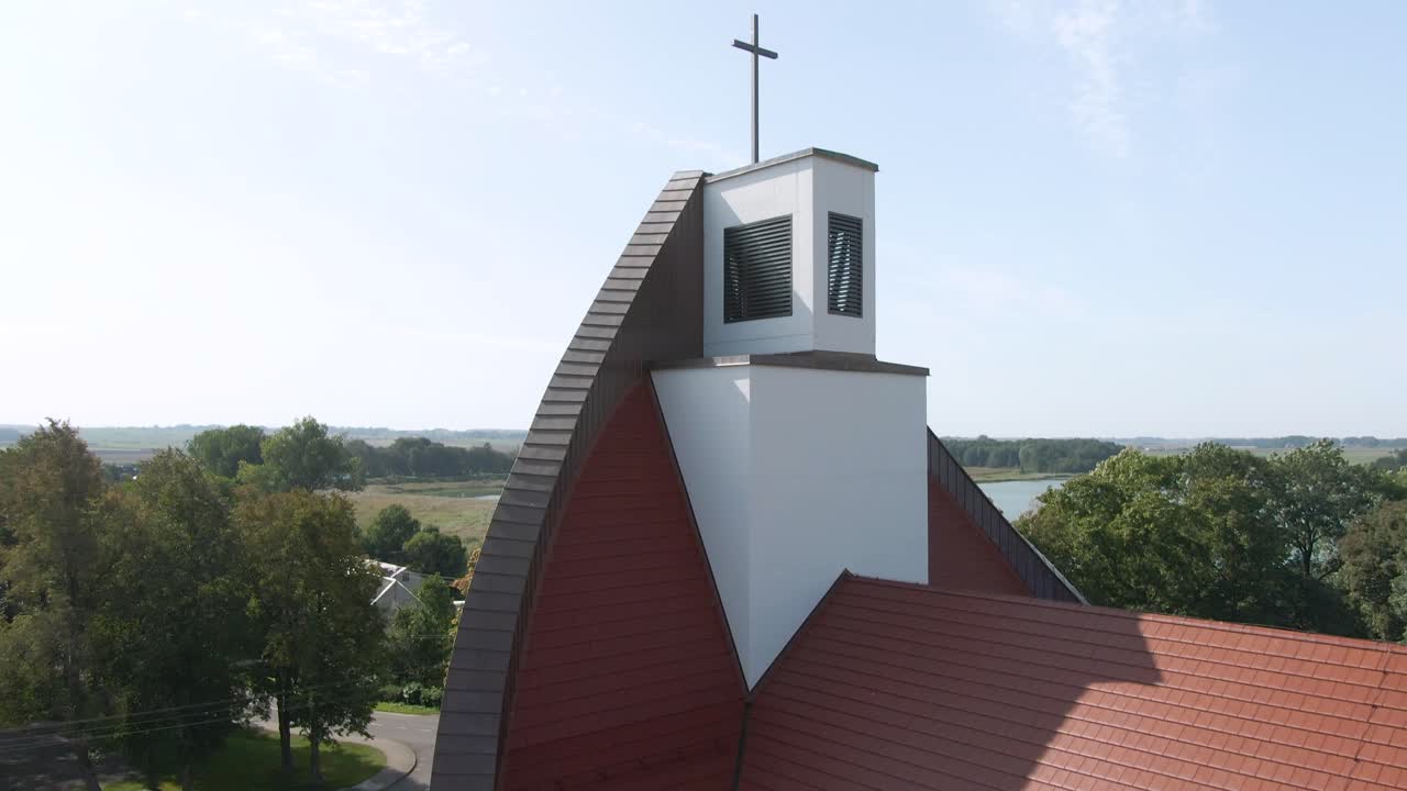 Drone ascending view from beautiful red roofed church and revealing bright blue sky of Lithuania, aerial drone shot