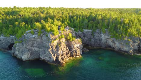 Aerial-flight-over-the-rocky-coast-of-Georgian-Bay,-with-its-turquoise-waters-and-dense-forest-in-Ontario,-Canada