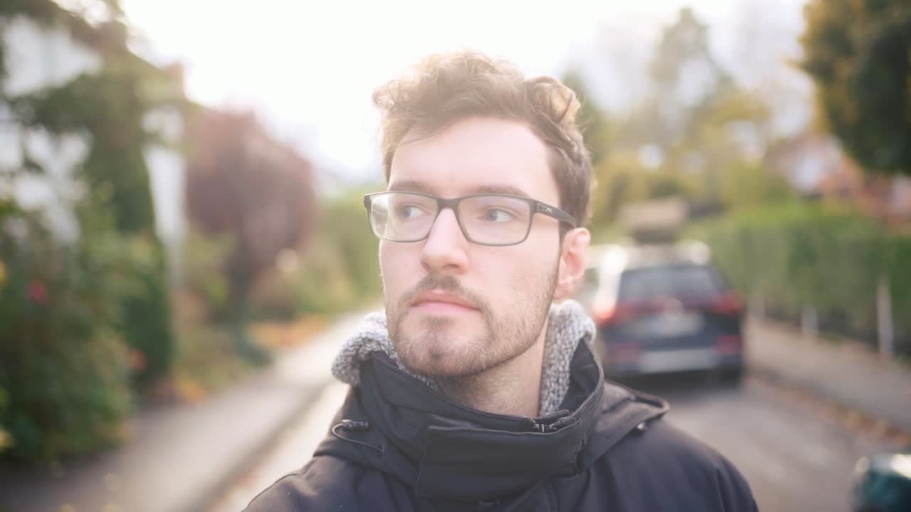 cámara lenta de un joven europeo vagando por los suburbios, vestido cálidamente, encarnando la esencia de un acogedor ambiente de otoño