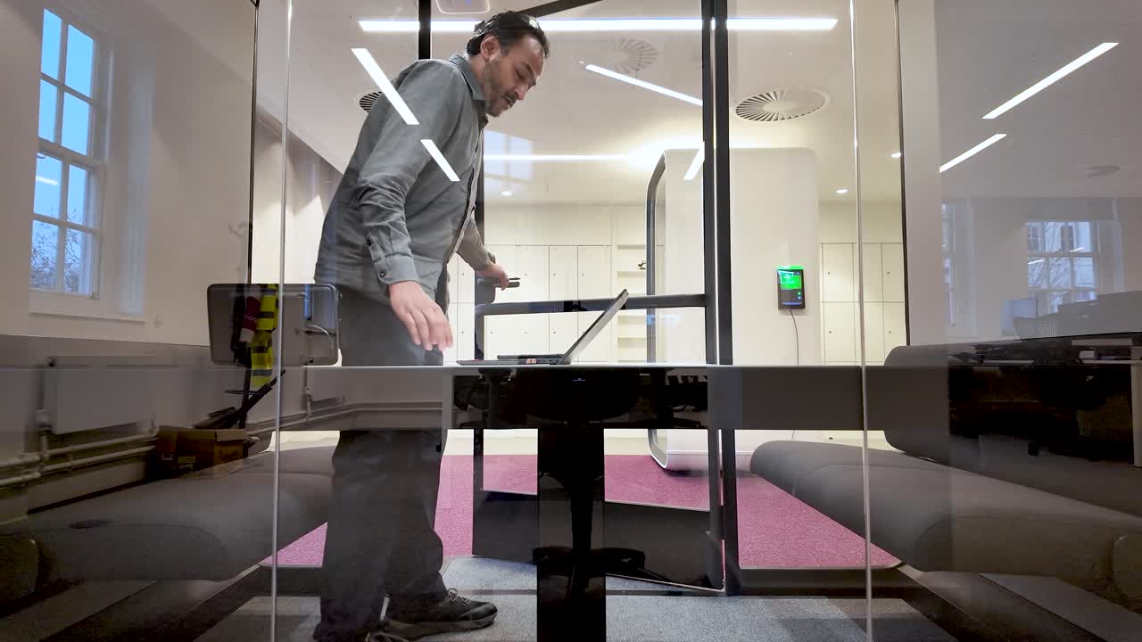 Cabina ufficio insonorizzata per riunioni online, uomo sud asiatico che entra in uno spazio di lavoro moderno per una videochiamata