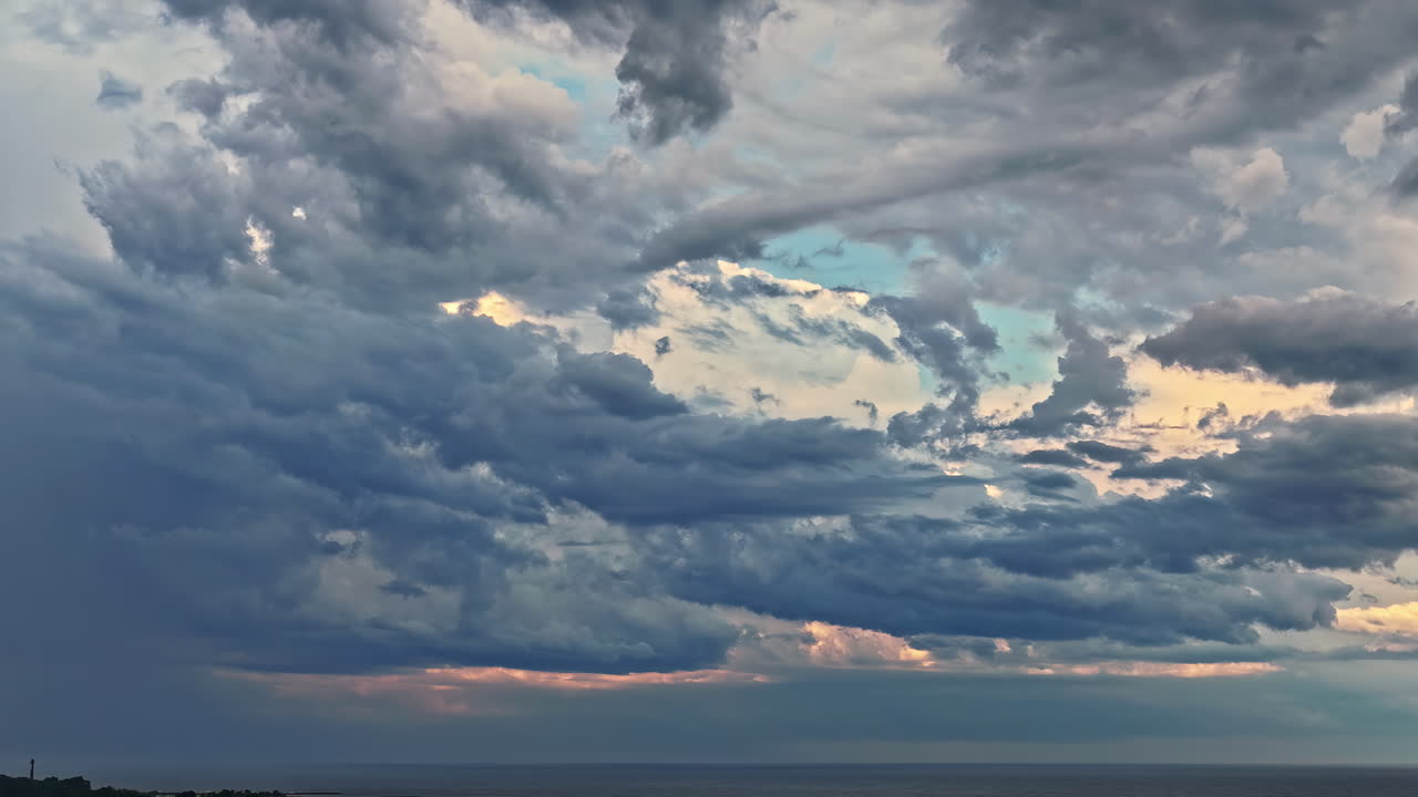 A stunning aerial parallax shot reveals layers of majestic and dramatic clouds, beautifully illuminated by the setting sun over the Baltic Sea