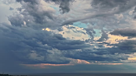 a stunning aerial parallax shot reveals layers of majestic and dramatic clouds, beautifully illuminated by the setting sun over the baltic sea