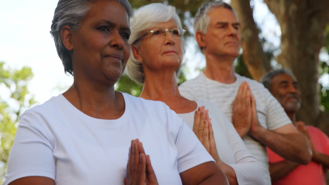 Senior friends performing yoga in garden 4k