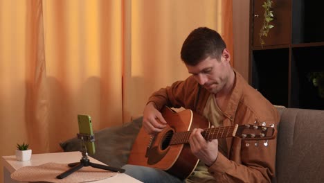hombre tocando la guitarra acústica en casa