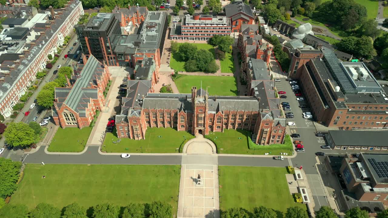 Wide, reversing overhead aerial video of Queen's University Belfast, and the university grounds in Northern Ireland on a bright and sunny day. Produced at 4K resolution, 60FPS and with Rec709 color.