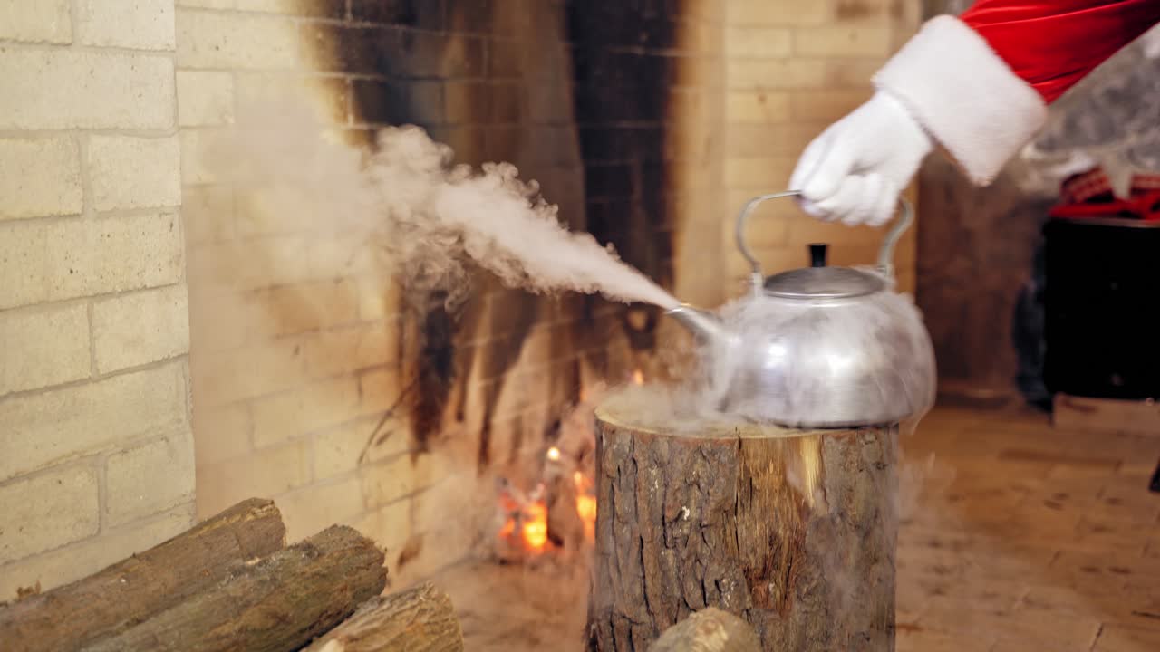 Close up of steaming teapot. Santa Claus's hand is taking the kettle. New Year and Christmas concept. Feast is coming.