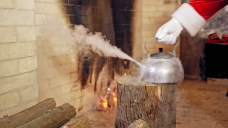 close up of steaming teapot. santa claus's hand is taking the kettle. new year and christmas concept. feast is coming.