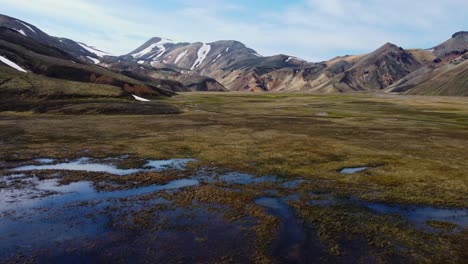 sky reflections and reveal of rainbow mountains of landmannalaugar covered in snow in iceland