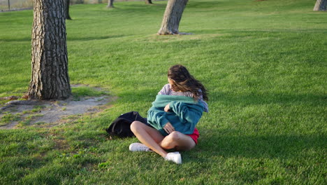 A-beautiful-young-hispanic-woman-in-a-park-trying-to-get-warm-and-cozy-with-her-sweater-in-cold-season-windy-weather