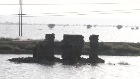 Franja-Elevada-De-Tierra-Que-Alberga-Tiendas-De-Campaña-Improvisadas-Rodeadas-De-Un-Paisaje-Inundado-En-Mehar,-Pakistán