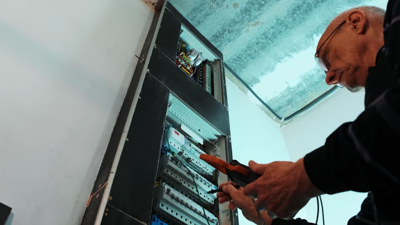 los electricistas ponen las manos a probar la corriente eléctrica en el panel de control. el ingeniero electricista trabaja midiendo el voltaje y la corriente de la línea eléctrica en el control del gabinete eléctrico.