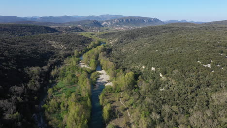 Beautiful-Herault-river-with-green-tall-trees-and-Cevennes-national-park-in-back